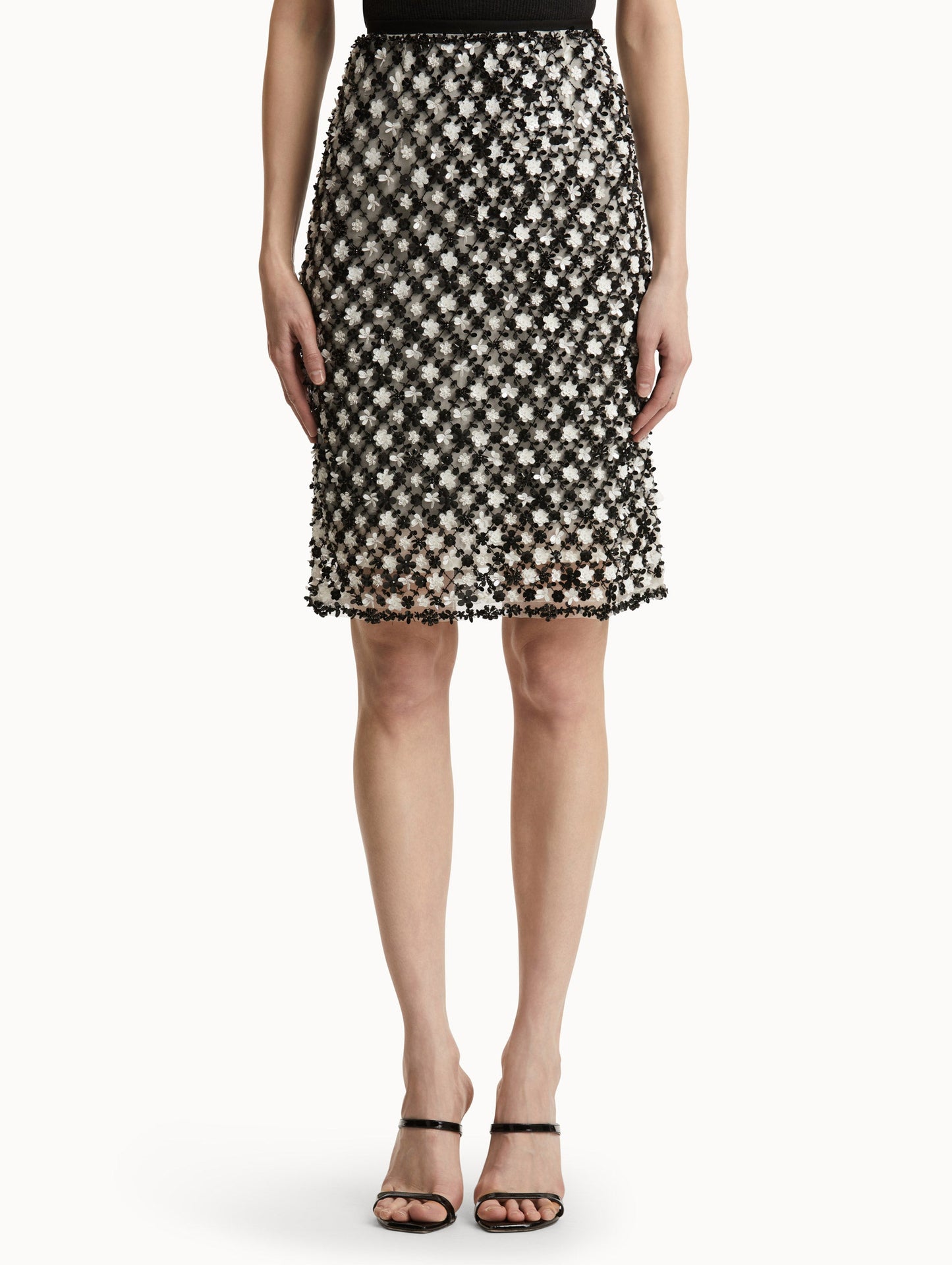 Front view of model wearing a high waisted black and ivory floral embroidered pencil skirt that follows a tweed pattern.