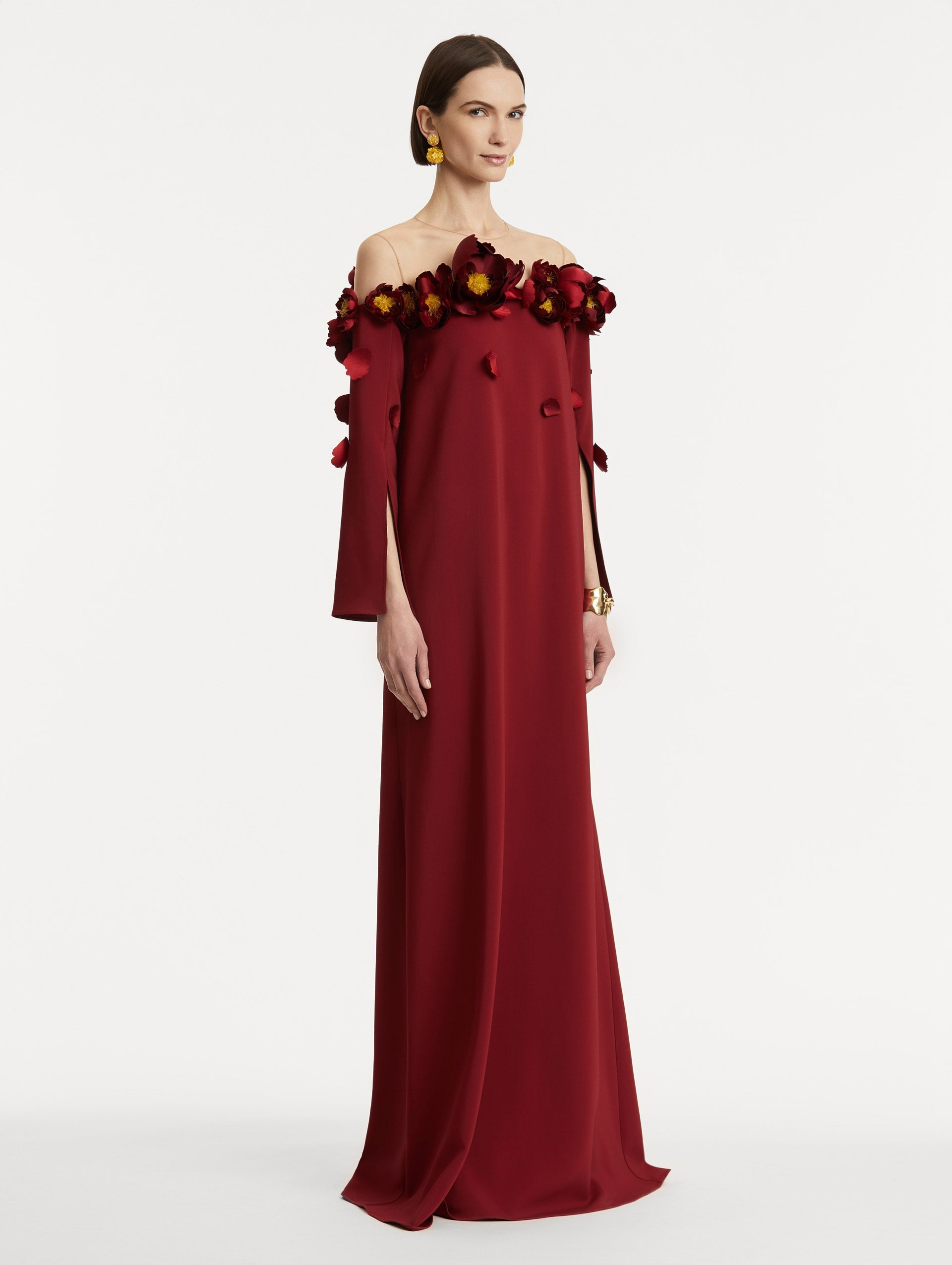 Full body side view of model wearing red split sleeve caftan with peony appliqués.