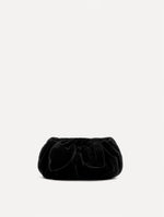 The Velvet Clutch in black features fabric folding, where the velvet is gathered and secured with a voluminous bow.