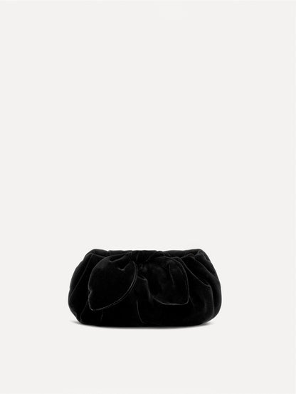 The Velvet Clutch in black features fabric folding, where the velvet is gathered and secured with a voluminous bow.
