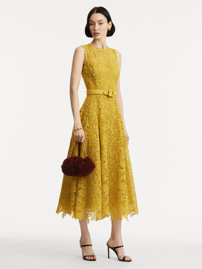 Full body image of the model wearing The Velvet Clutch which features dark red fabric folding, where the velvet is gathered and secured with a voluminous bow and a gold chain with the Oscar 'O'.