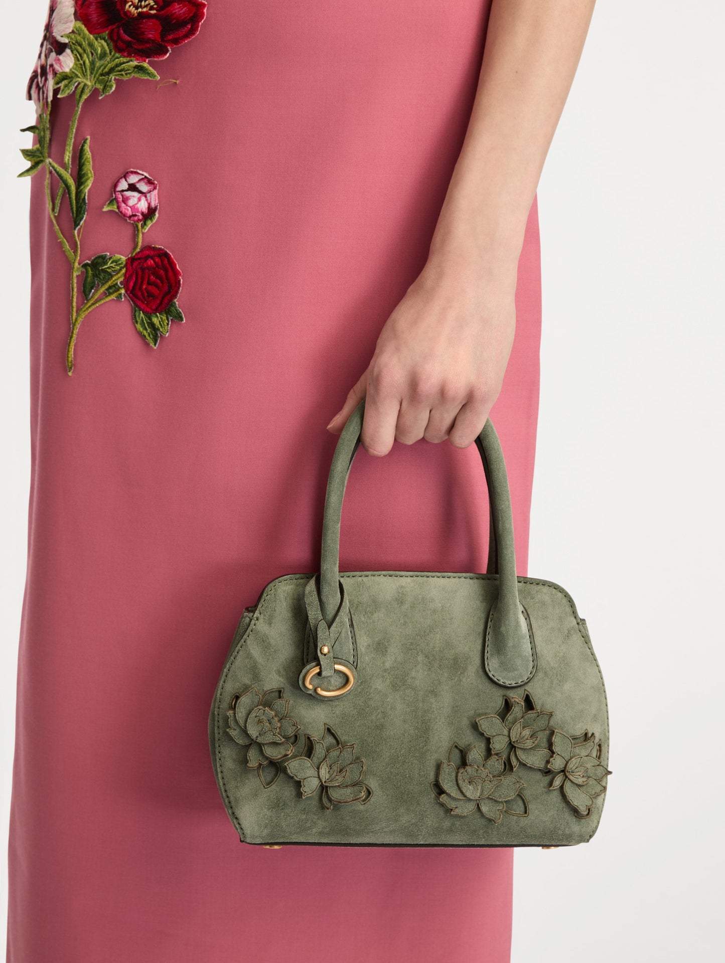 The Mini Ivy With Laser Cut Flowers in sage has a compartment with top handles and a removeable shoulder strap with various Oscar 'O' emblems on the hangtag and magnetic closure.
