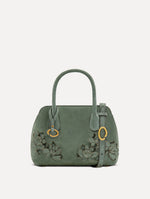 The Mini Ivy With Laser Cut Flowers in sage has a compartment with top handles and a removeable shoulder strap with various Oscar 'O' emblems on the hangtag and magnetic closure.