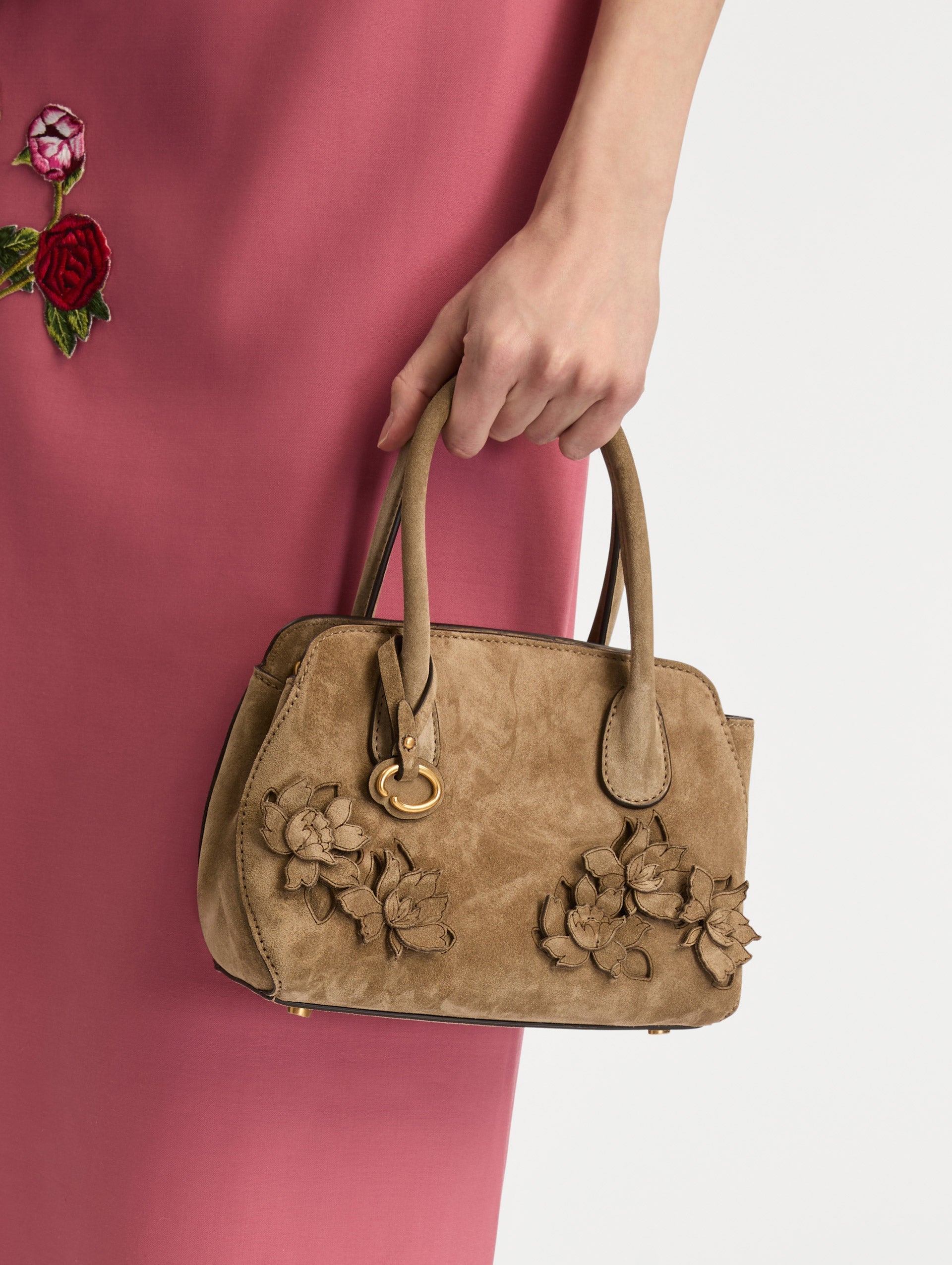 The Mini Ivy With Laser Cut Flowers in taupe has a compartment with top handles and a removeable shoulder strap with various Oscar 'O' emblems on the hangtag and magnetic closure.