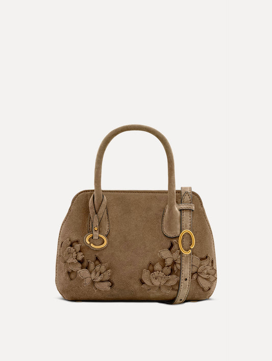 The Mini Ivy With Laser Cut Flowers in taupe has a compartment with top handles and a removeable shoulder strap with various Oscar 'O' emblems on the hangtag and magnetic closure.