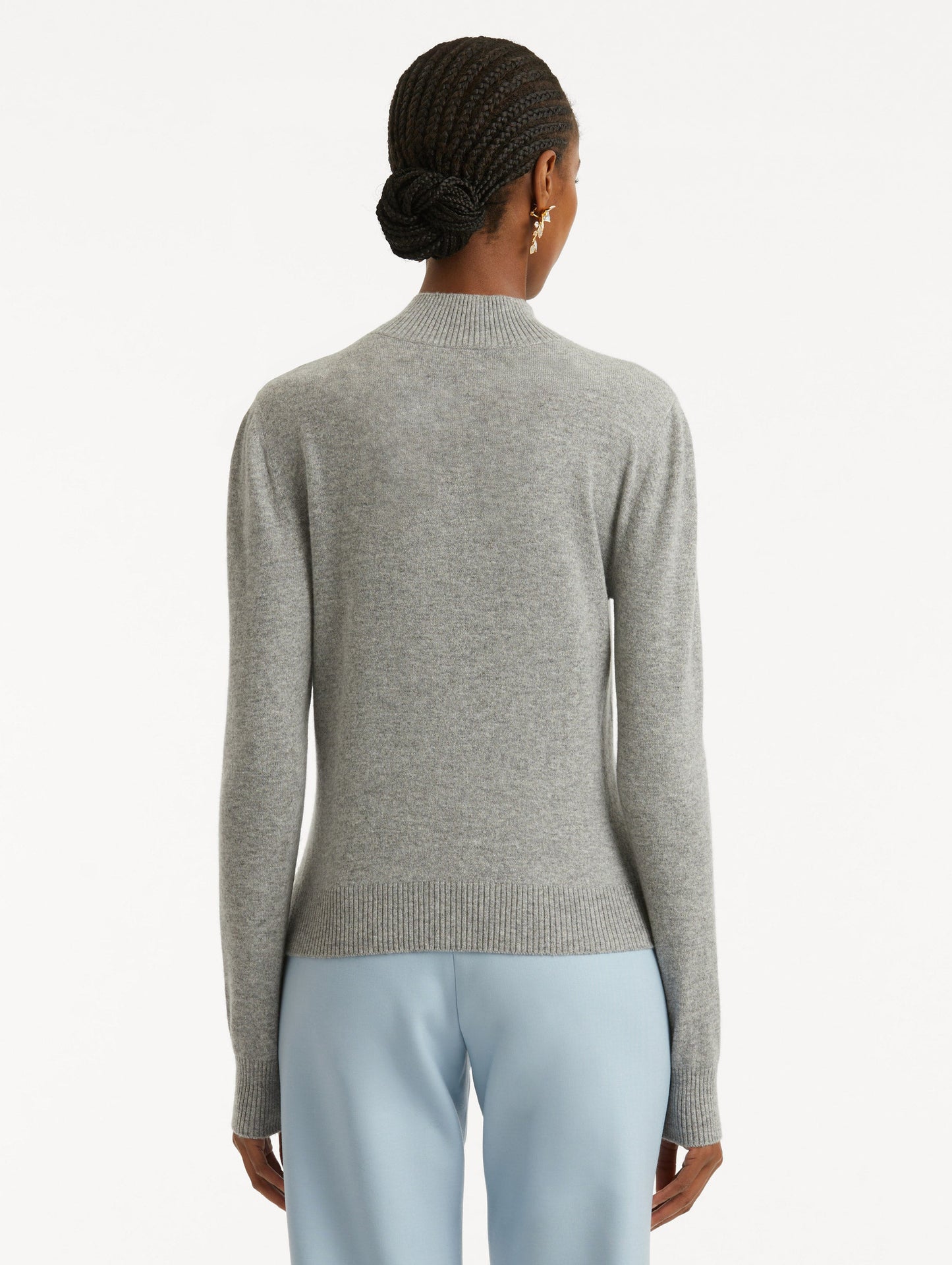 Back view of model wearing light grey pullover with long sleeves and a crew neckline.
