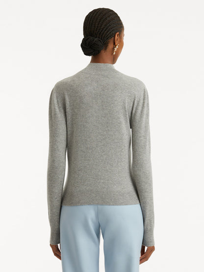 Back view of model wearing light grey pullover with long sleeves and a crew neckline.