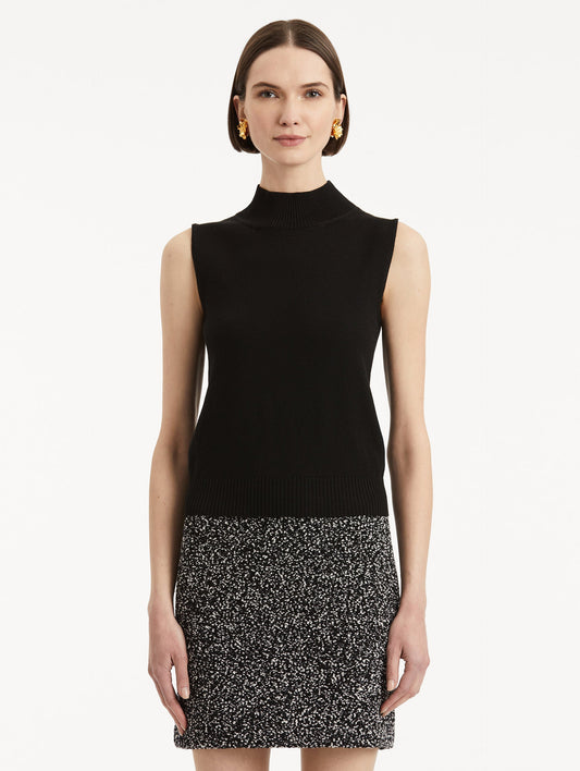 Front view of model wearing black pullover with mock neckline and ribbed trim.