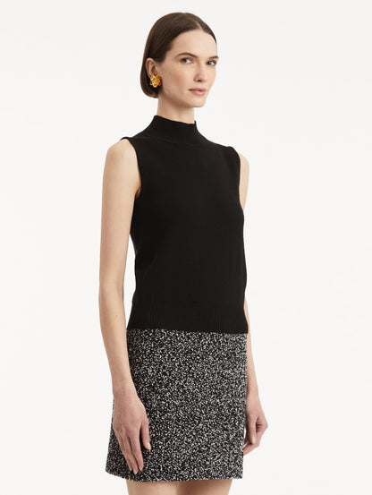 Side view of model wearing black pullover with mock neckline and ribbed trim.