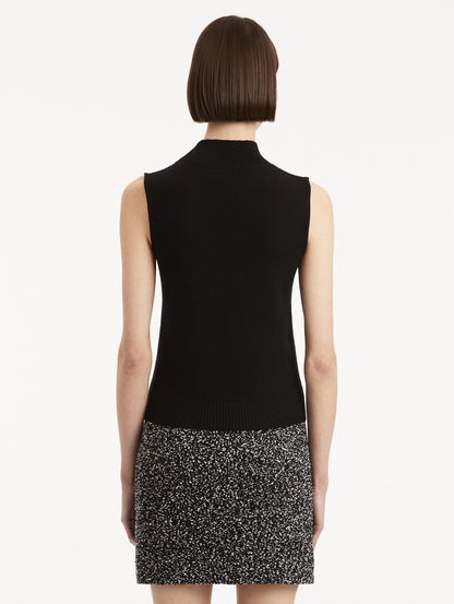 Back view of model wearing black pullover with mock neckline and ribbed trim.