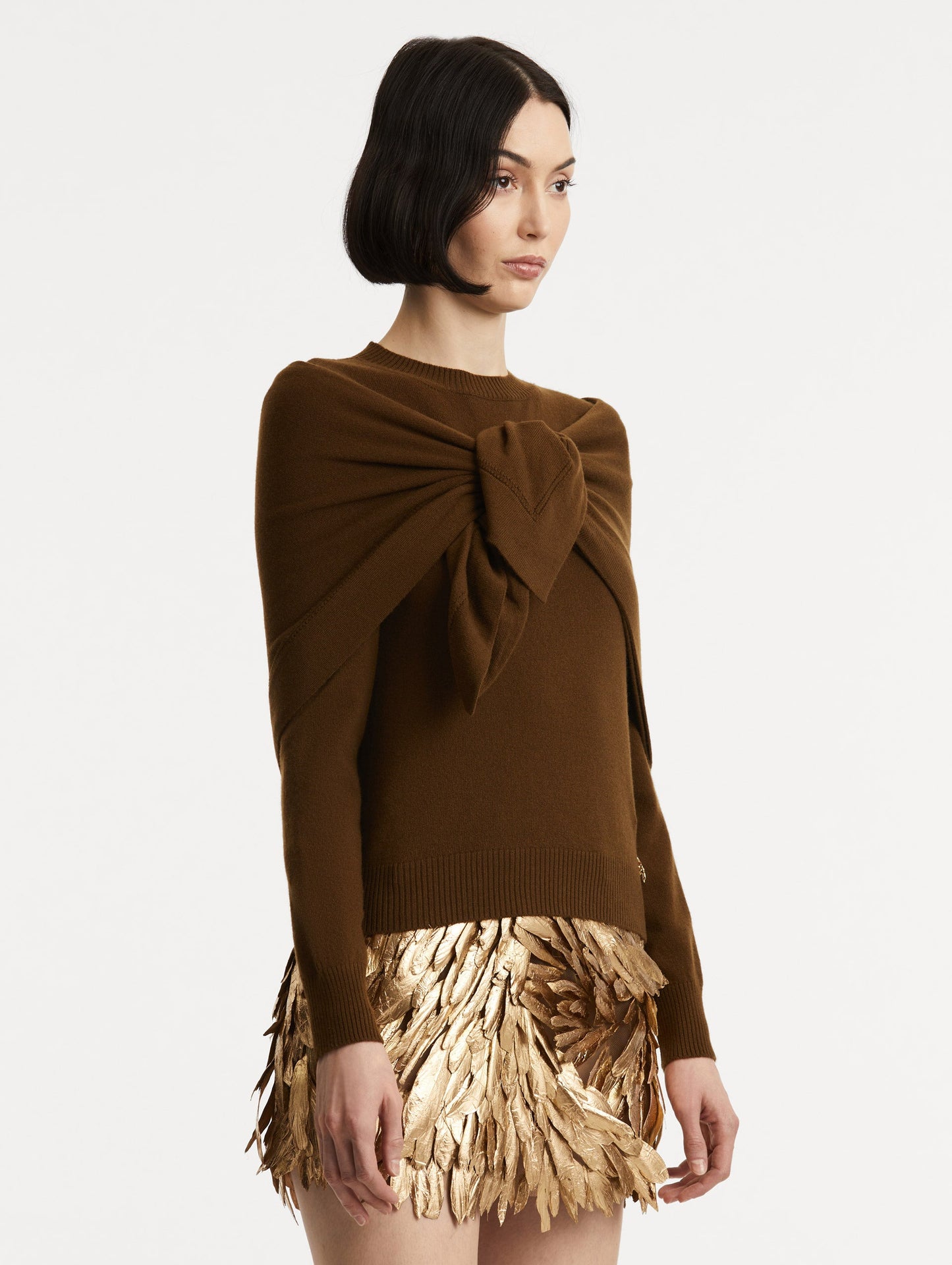Side view of model wearing brown pullover with long sleeves and a crew neckline. Features matching shawl draped over shoulders and tied in front.