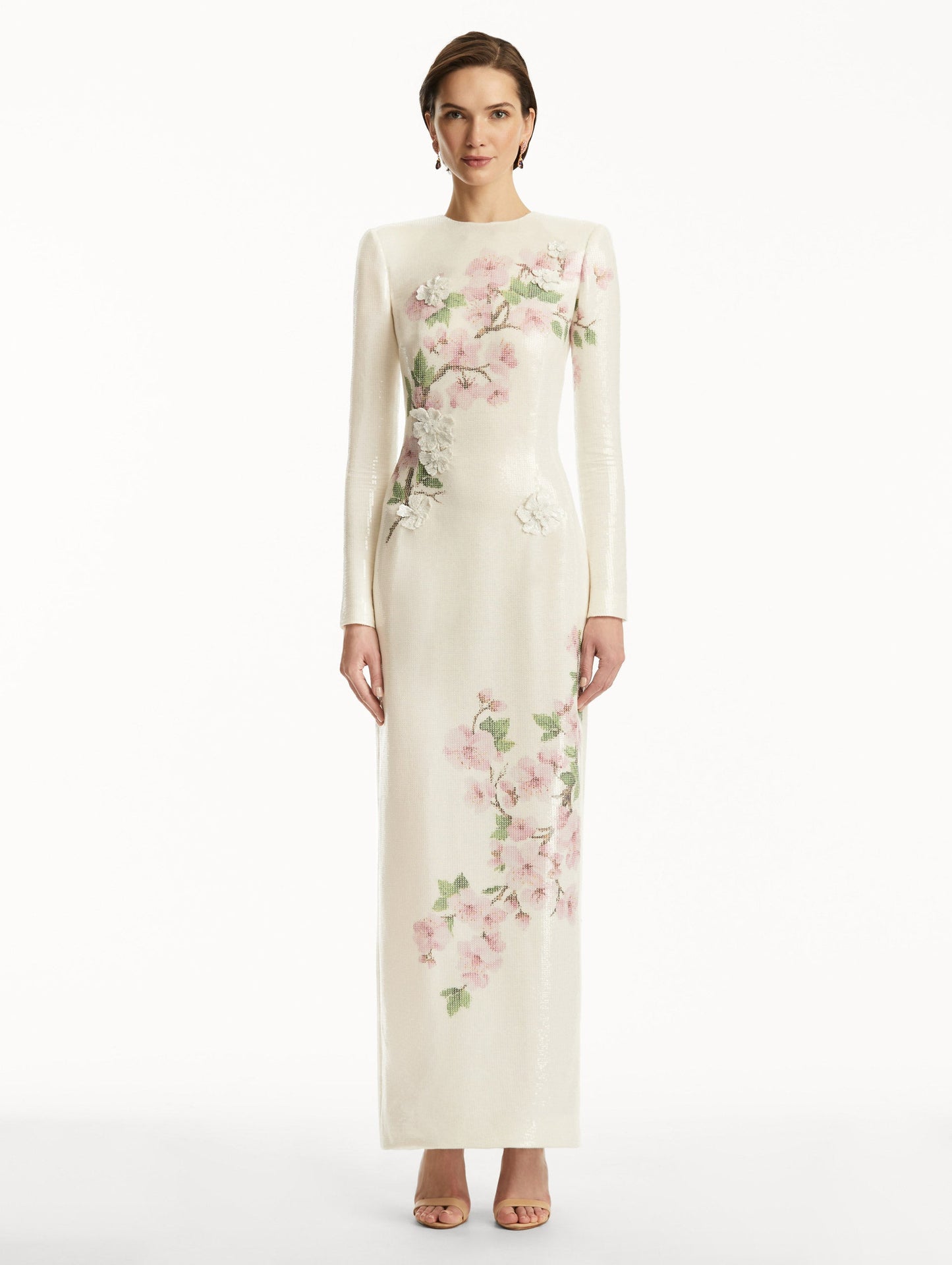 Model wearing white long sleeve sequin gown with pink cherry blossoms. Front View