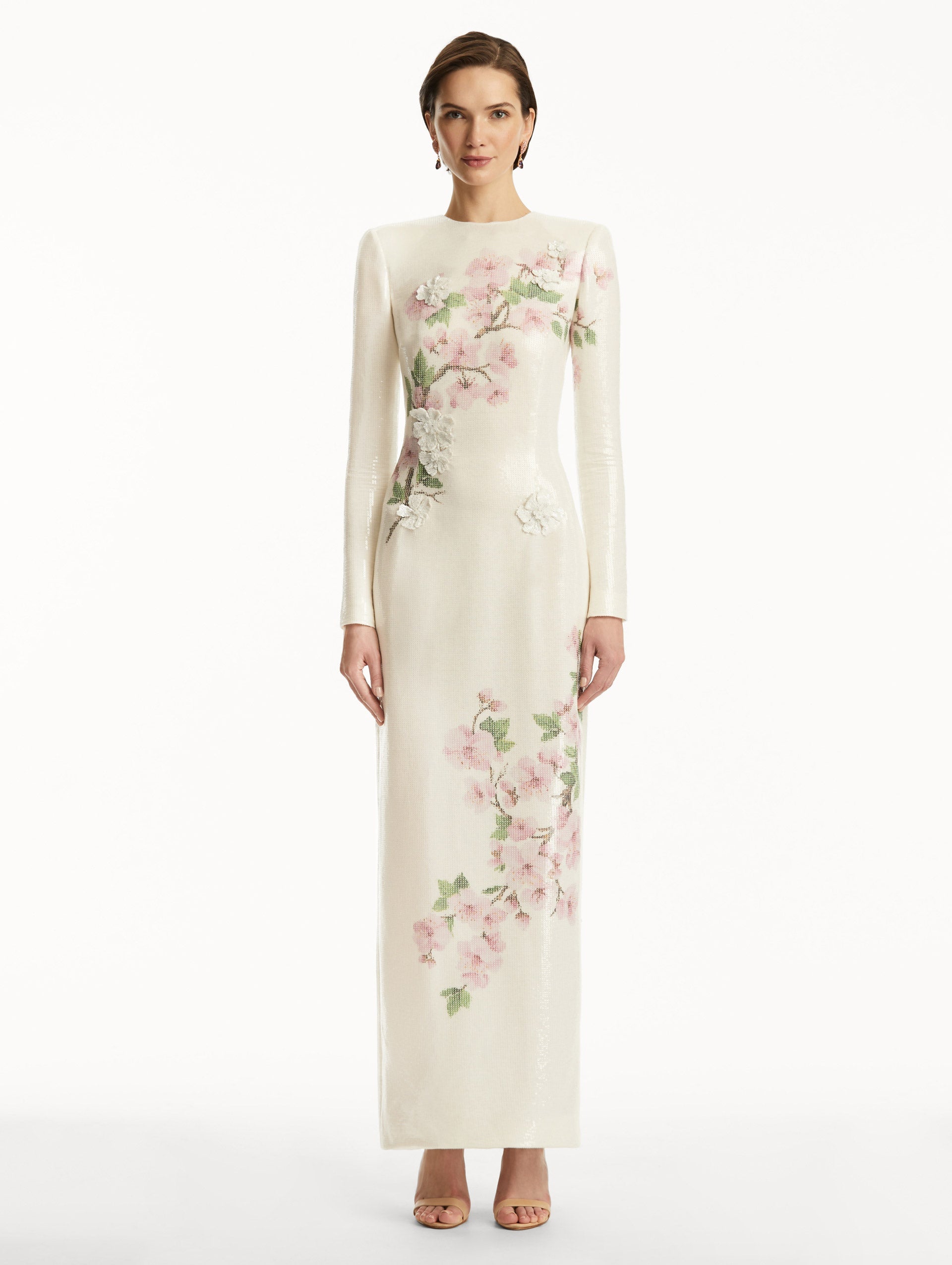 Model wearing white long sleeve sequin gown with pink cherry blossoms. Front View