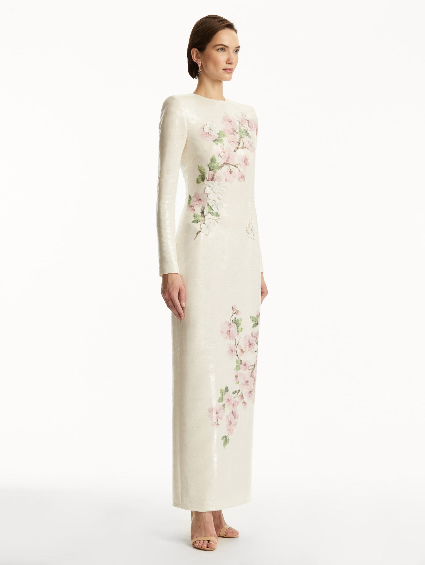 Model wearing white long sleeve sequin gown with pink cherry blossoms. Side View