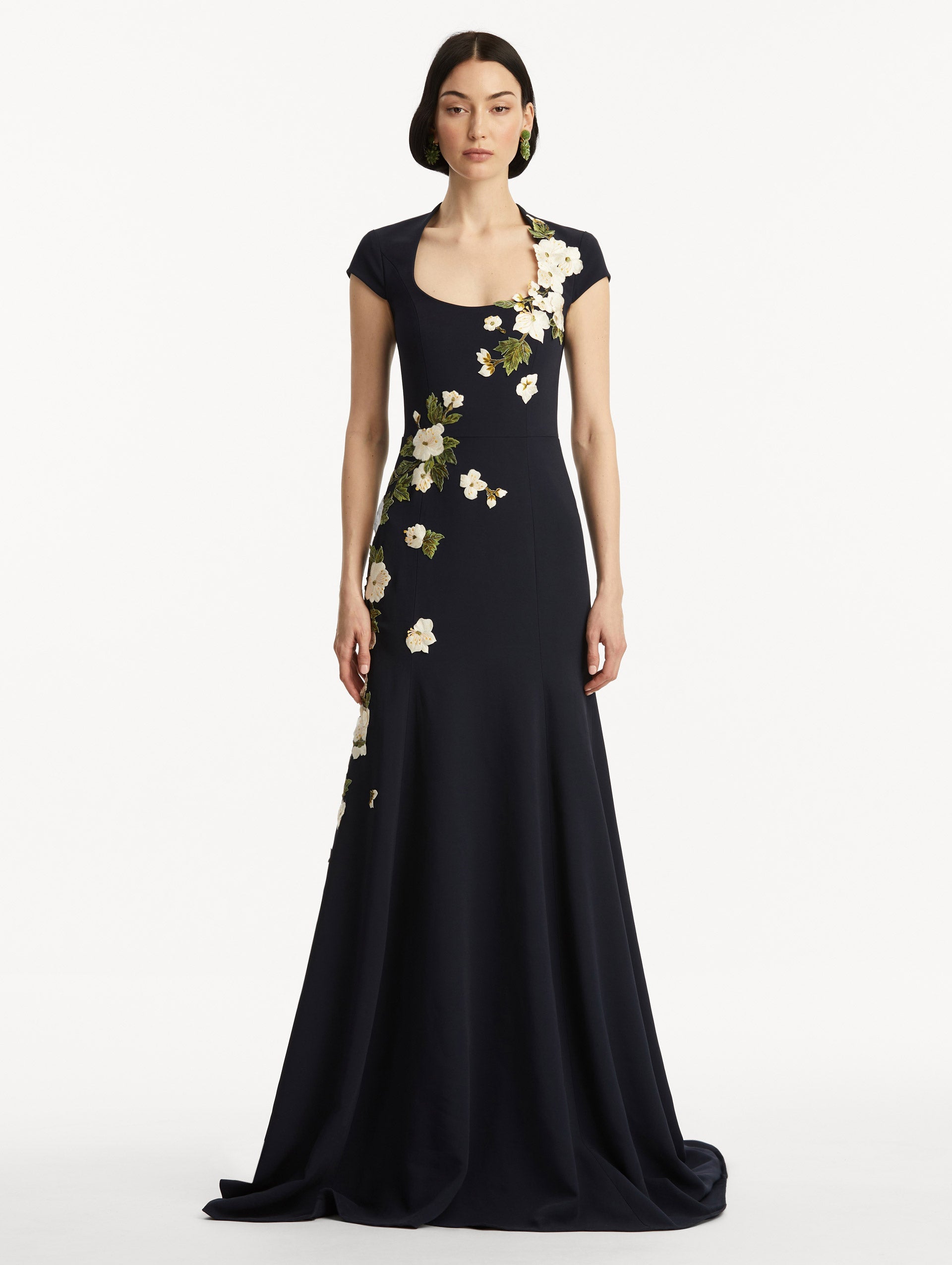 Model wearing short sleeve navy gown with white cherry blossoms embroidered. Front view