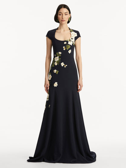 Model wearing short sleeve navy gown with white cherry blossoms embroidered. Front view