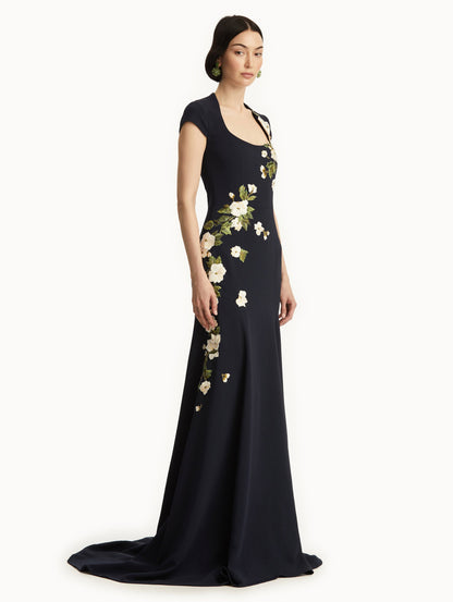 Model wearing short sleeve navy gown with white cherry blossoms embroidered. Side view