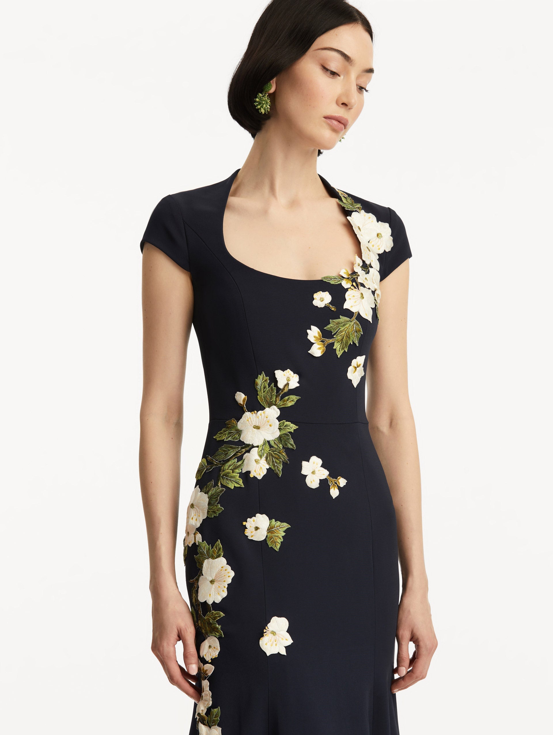 Model wearing short sleeve navy gown with white cherry blossoms embroidered. Zoom view