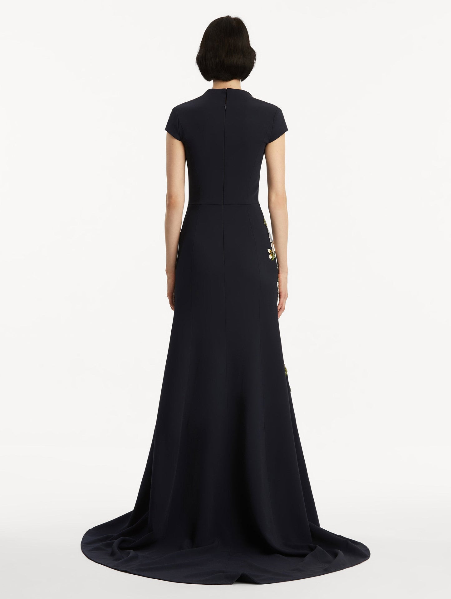 Model wearing short sleeve navy gown with white cherry blossoms embroidered. Back view