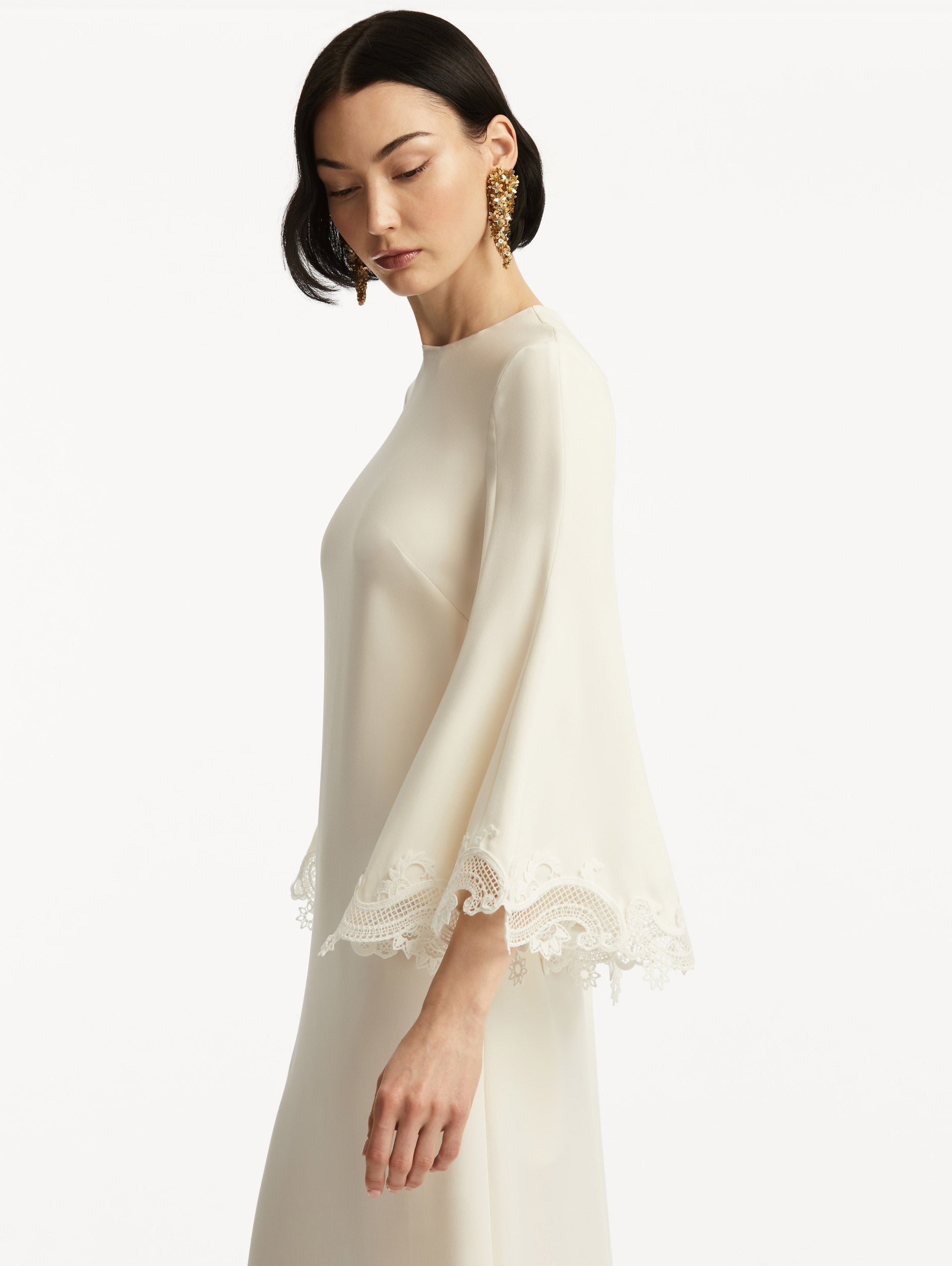 Model wearing white long sleeve caftan with lace detail on the cuff of the bell sleeves. Zoom view.