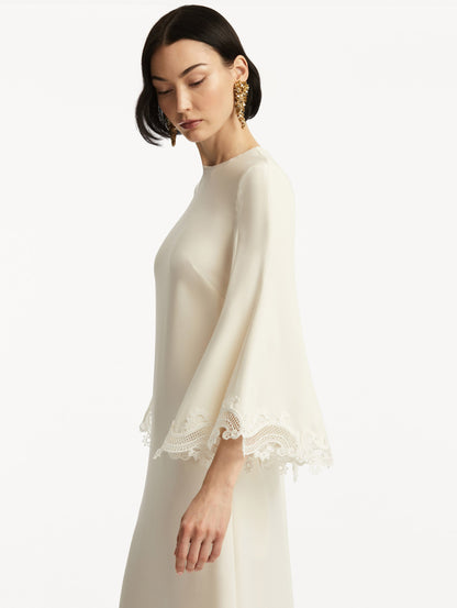 Model wearing white long sleeve caftan with lace detail on the cuff of the bell sleeves. Zoom view.