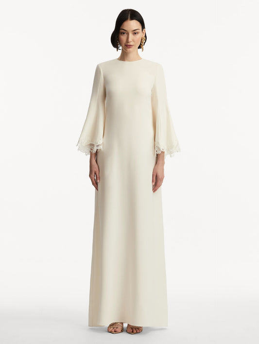 Model wearing white long sleeve caftan with lace detail on the cuff of the bell sleeves. Front view.