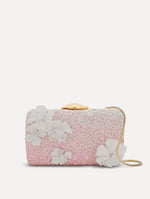 A clutch embellished with pink stones and three-dimensional white flowers attached. Front view.