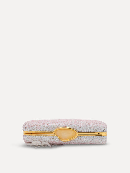 A clutch embellished with pink stones and three-dimensional white flowers attached. Top view.