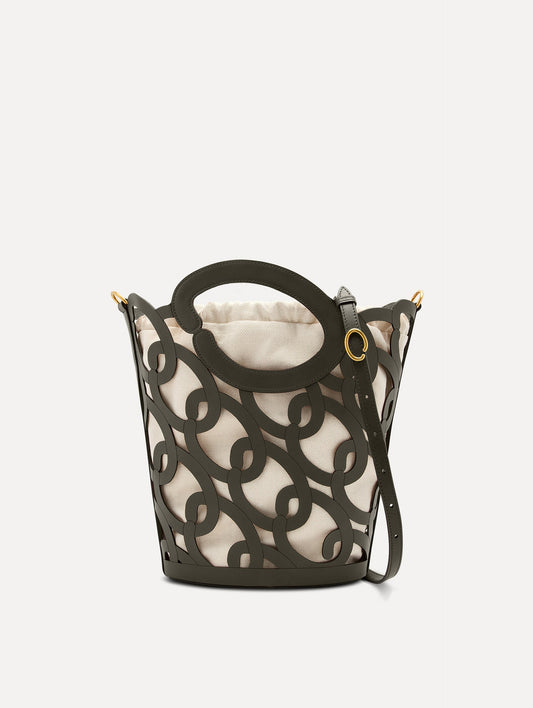 The Oscar chain link bucket tote in olive green with a large o forming the top handle and detachable shoulder strap, paired with an ombre floral dress. Front View.