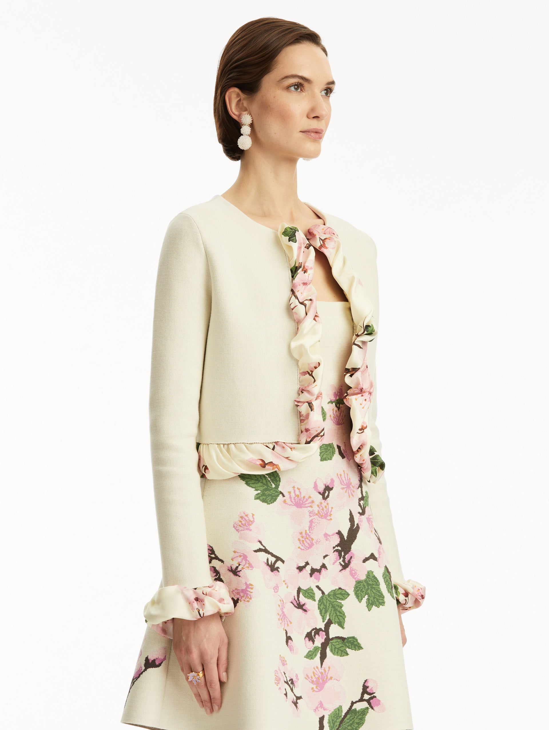 White cardigan with pink bubble twist trim printed with cherry blossoms, paired with cherry blossom tweed dress. Side view