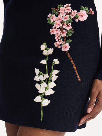 The model is wearing the mixed botanical embroidered dress with an A-line silhouette in a navy wool blend. Zoom view.