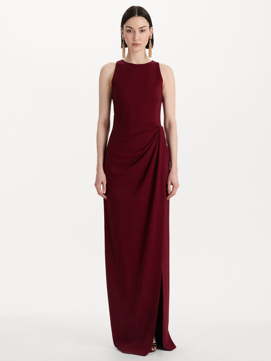 The model is wearing the drape-detailed cady gown with a sleeveless silhouette in the color claret. Front view.