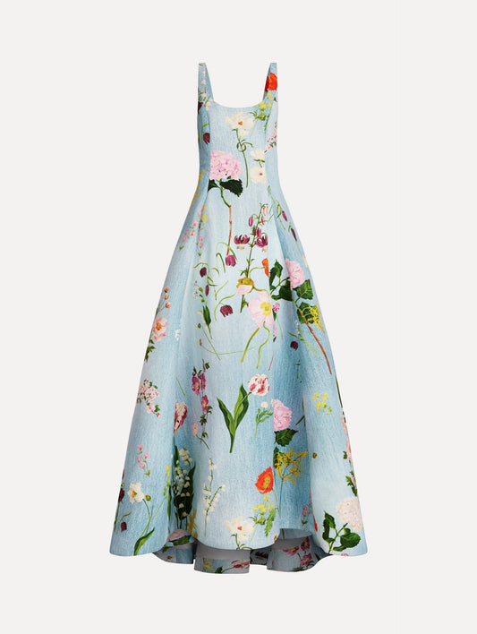 The model is wearing the mixed botanical faille gown with a sleeveless scoop neckline and a bold floral print in blue multi.