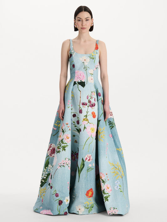 The model is wearing the mixed botanical faille gown with a sleeveless scoop neckline and a bold floral print in blue multi. Front view.