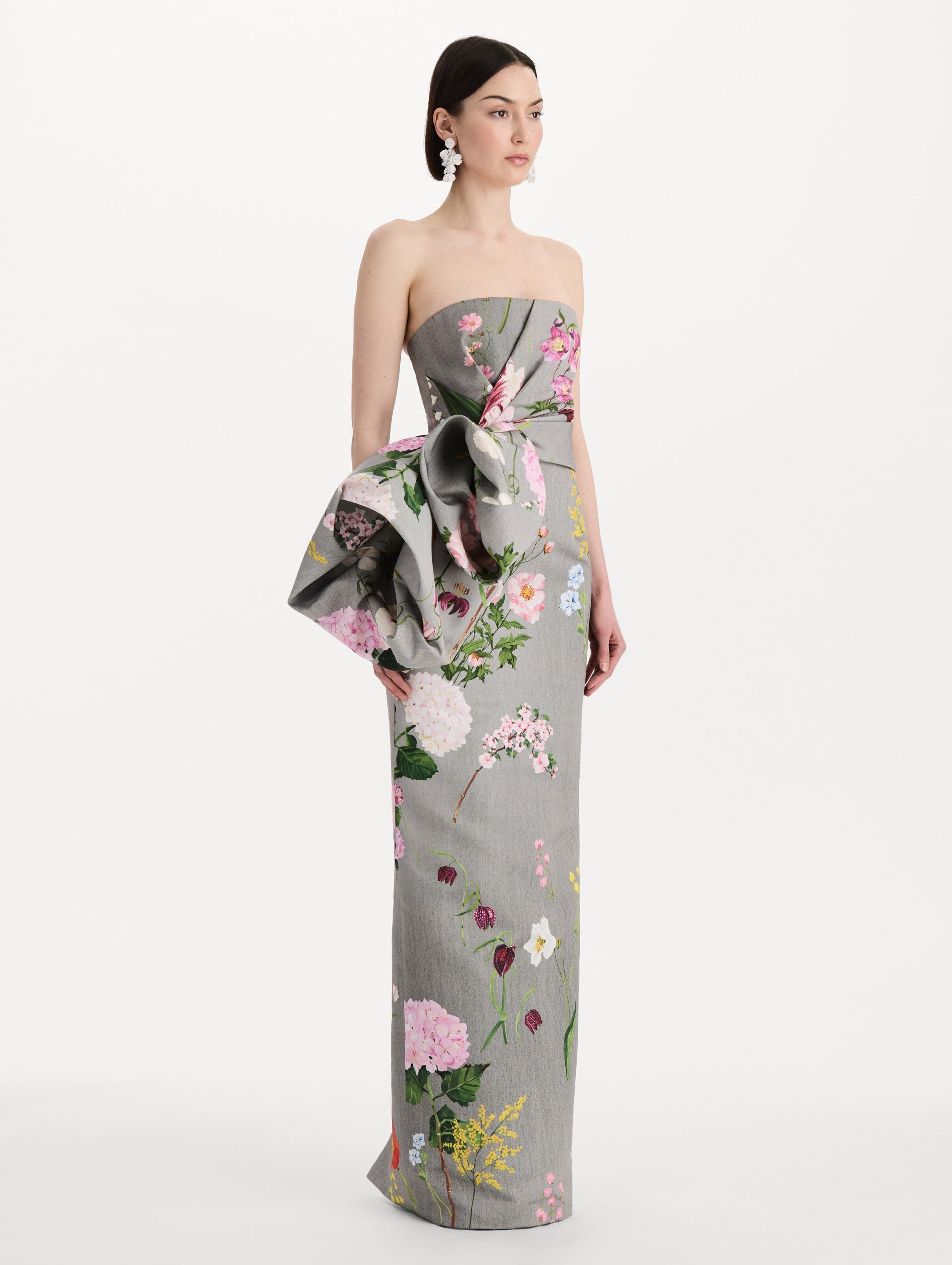 The model is wearing the mixed botanical drape-detailed faille gown with a strapless silhouette in the color grey multi. Side view.