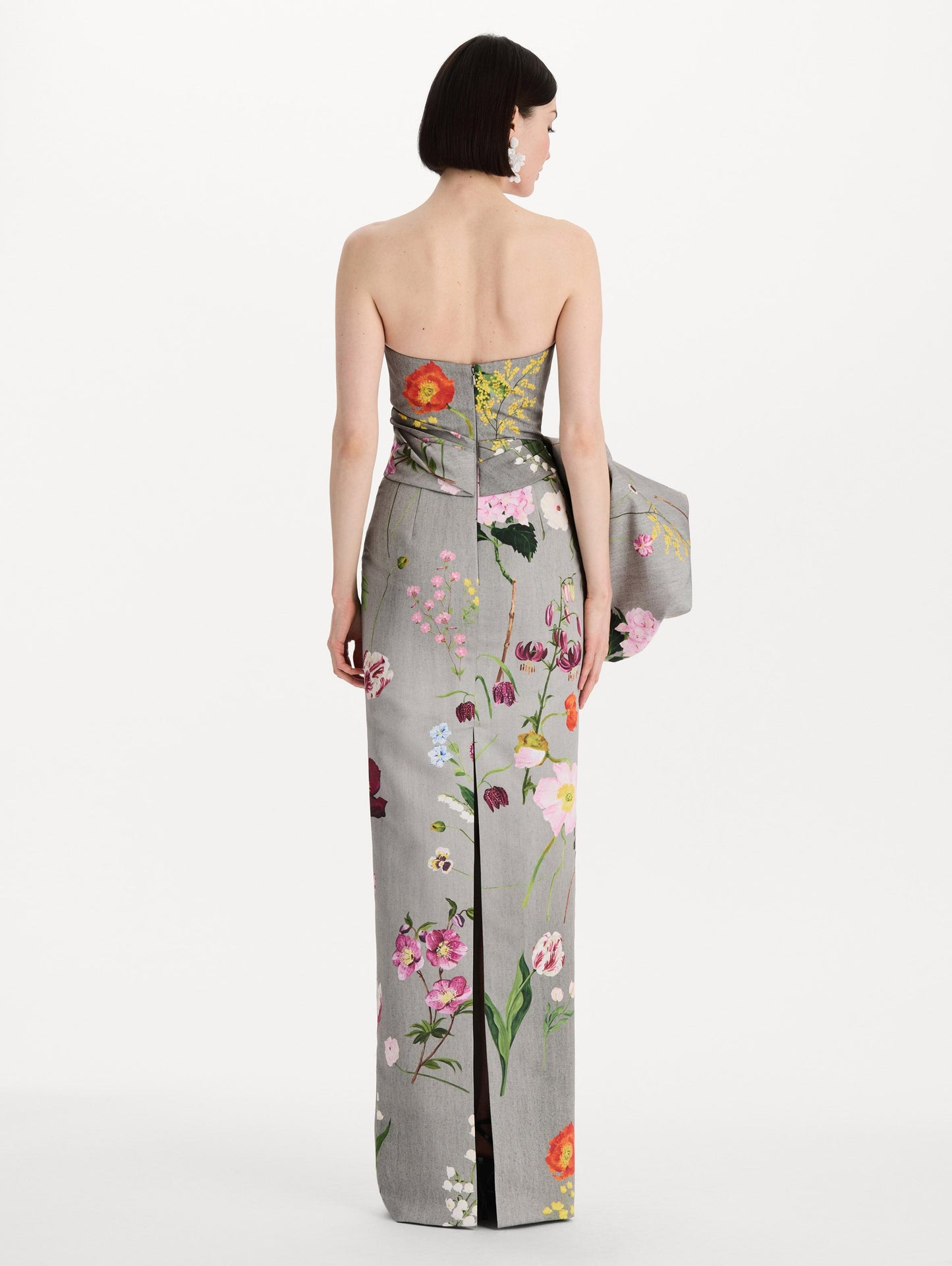 The model is wearing the mixed botanical drape-detailed faille gown with a strapless silhouette in the color grey multi. Back view.
