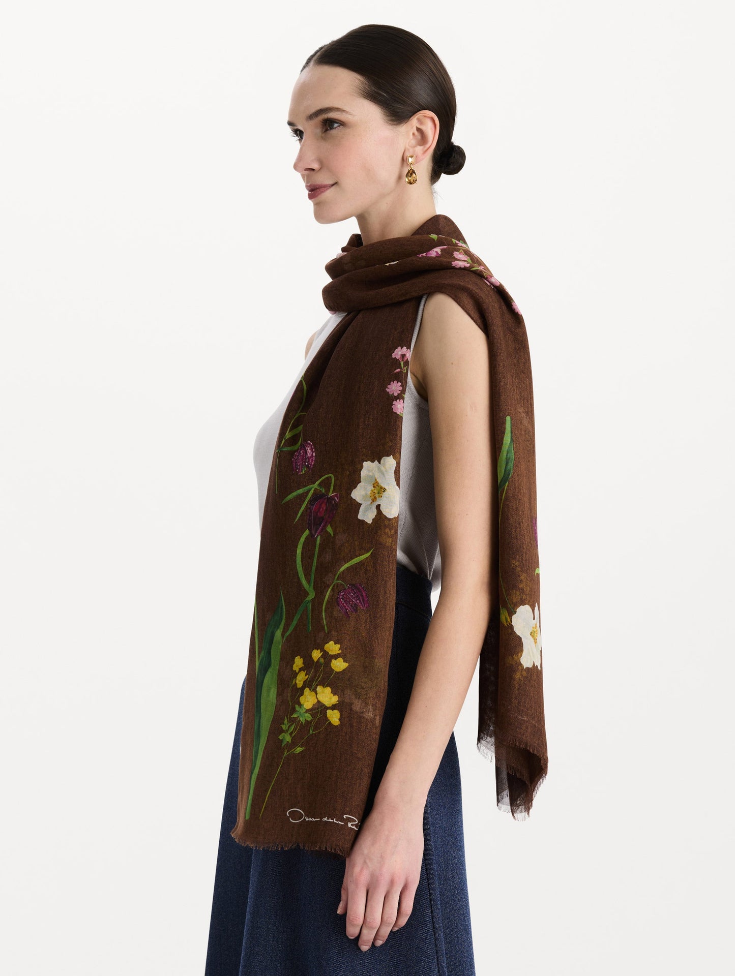 The model is wearing the mixed botanical scarf with an all-over floral print in the color brown. Side view.