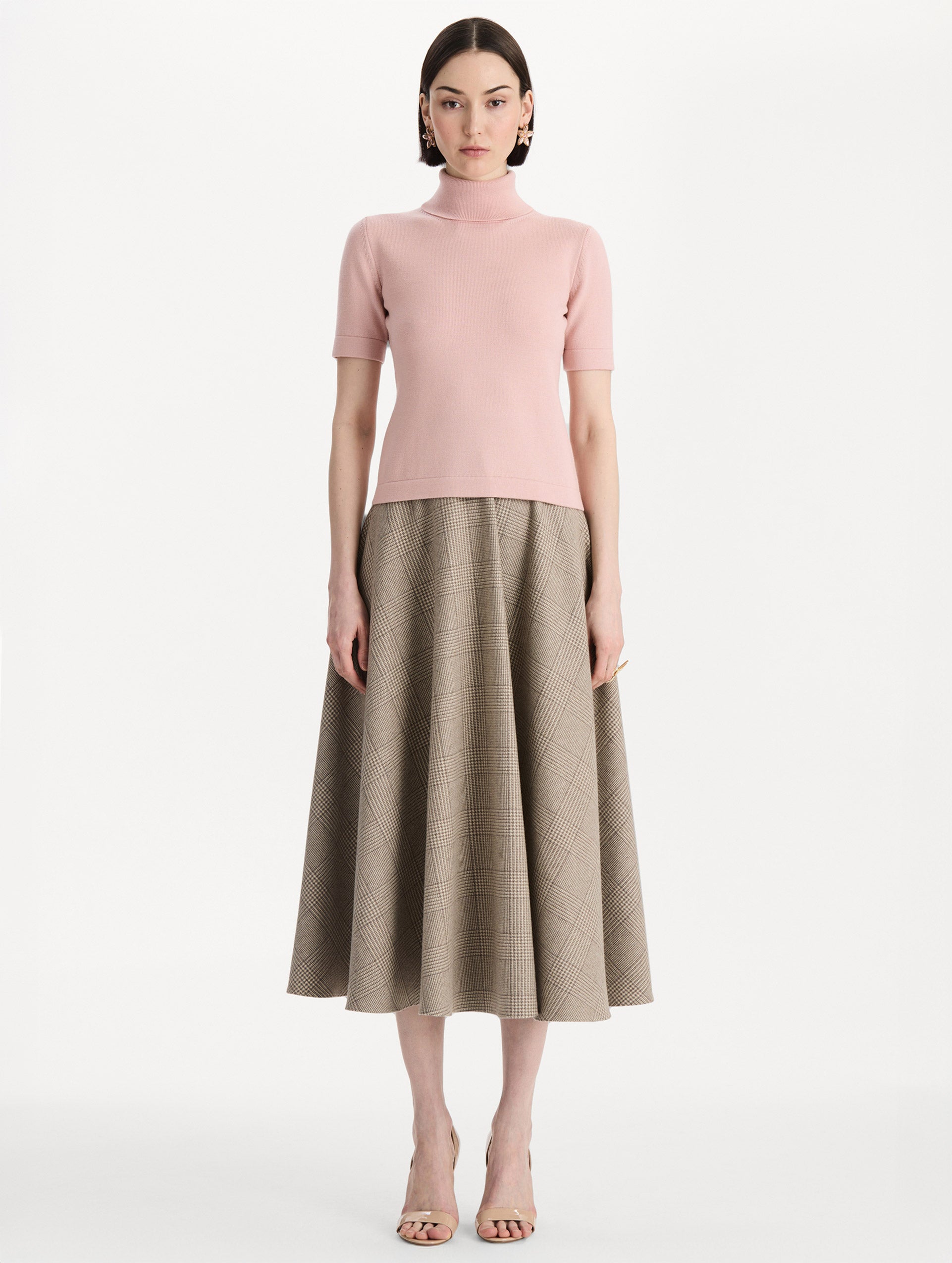 The model is wearing the turtleneck wool short-sleeve pullover with a fold-over neckline in the color blush. Front view.