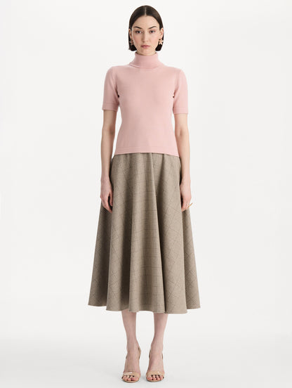 The model is wearing the turtleneck wool short-sleeve pullover with a fold-over neckline in the color blush. Front view.