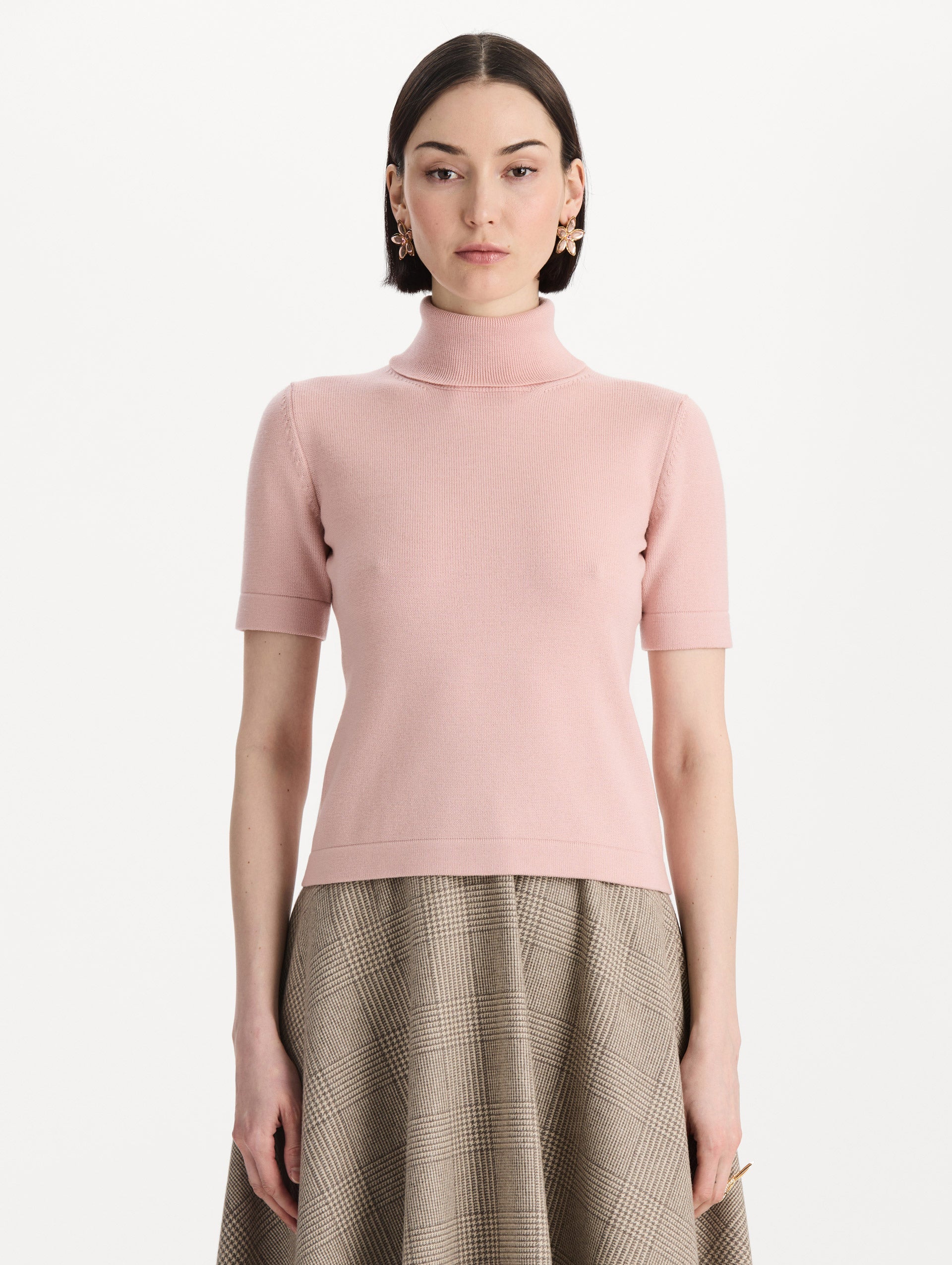 The model is wearing the turtleneck wool short-sleeve pullover with a fold-over neckline in the color blush. Front view.