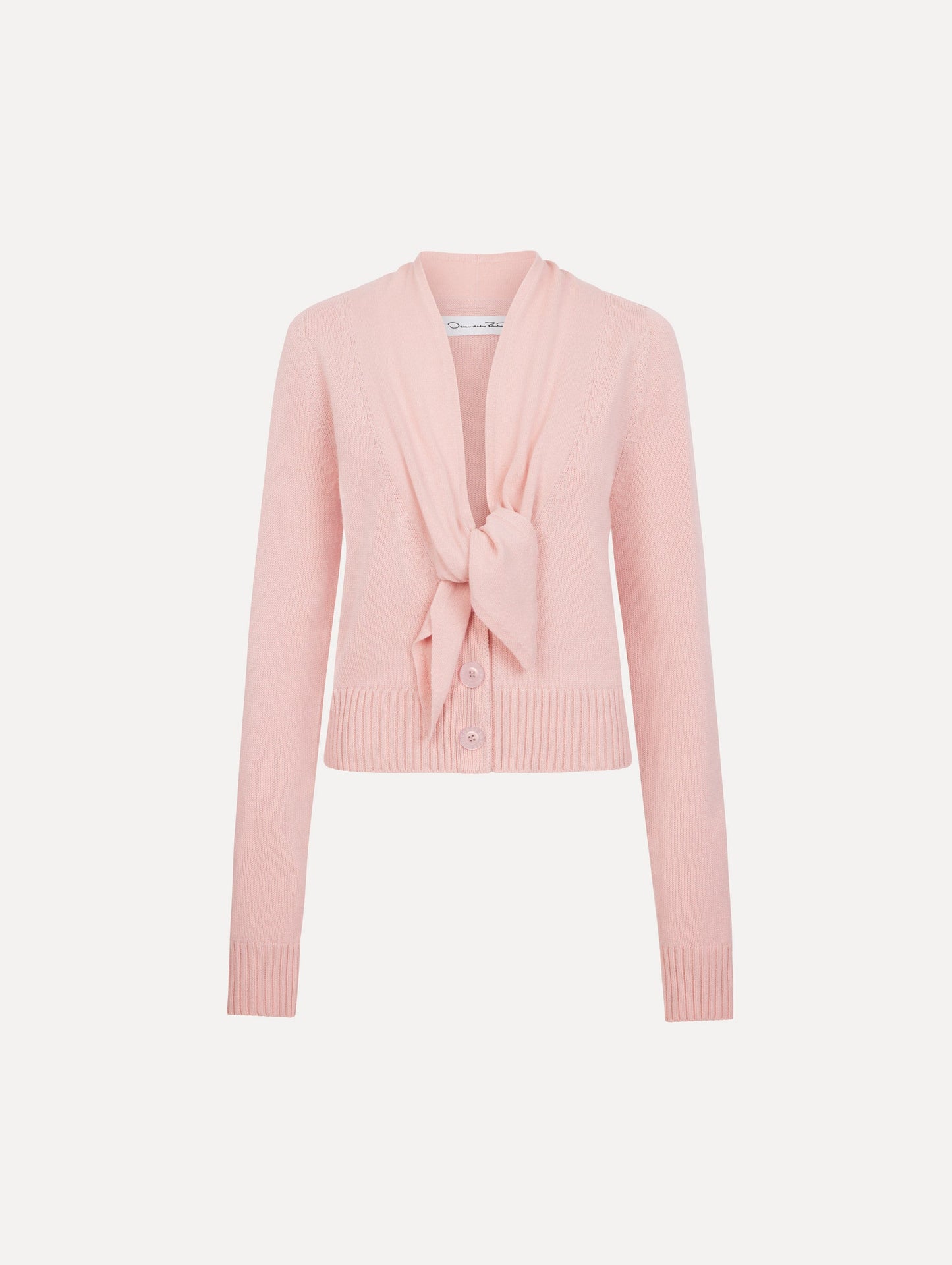 The model is wearing the tie-neck cardigan in blush wool with a tie V-neck detail.