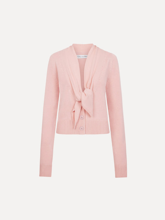 The model is wearing the tie-neck cardigan in blush wool with a tie V-neck detail.