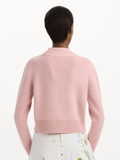 The model is wearing the tie-neck cardigan in blush wool with a tie V-neck detail. Back view.