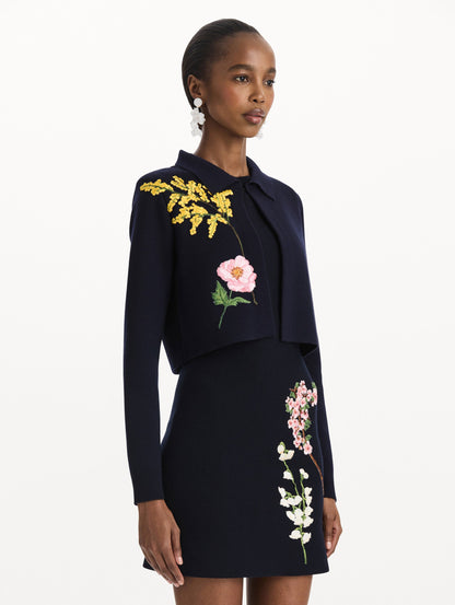 The model is wearing the mixed botanical cropped jacket with delicate embroidery in the color navy. Side view.