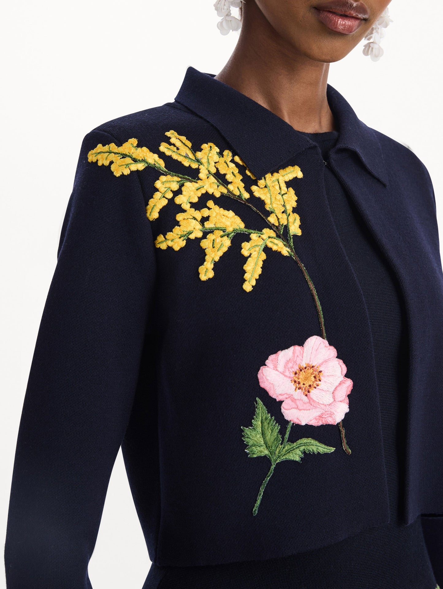 The model is wearing the mixed botanical cropped jacket with delicate embroidery in the color navy. Zoom view.