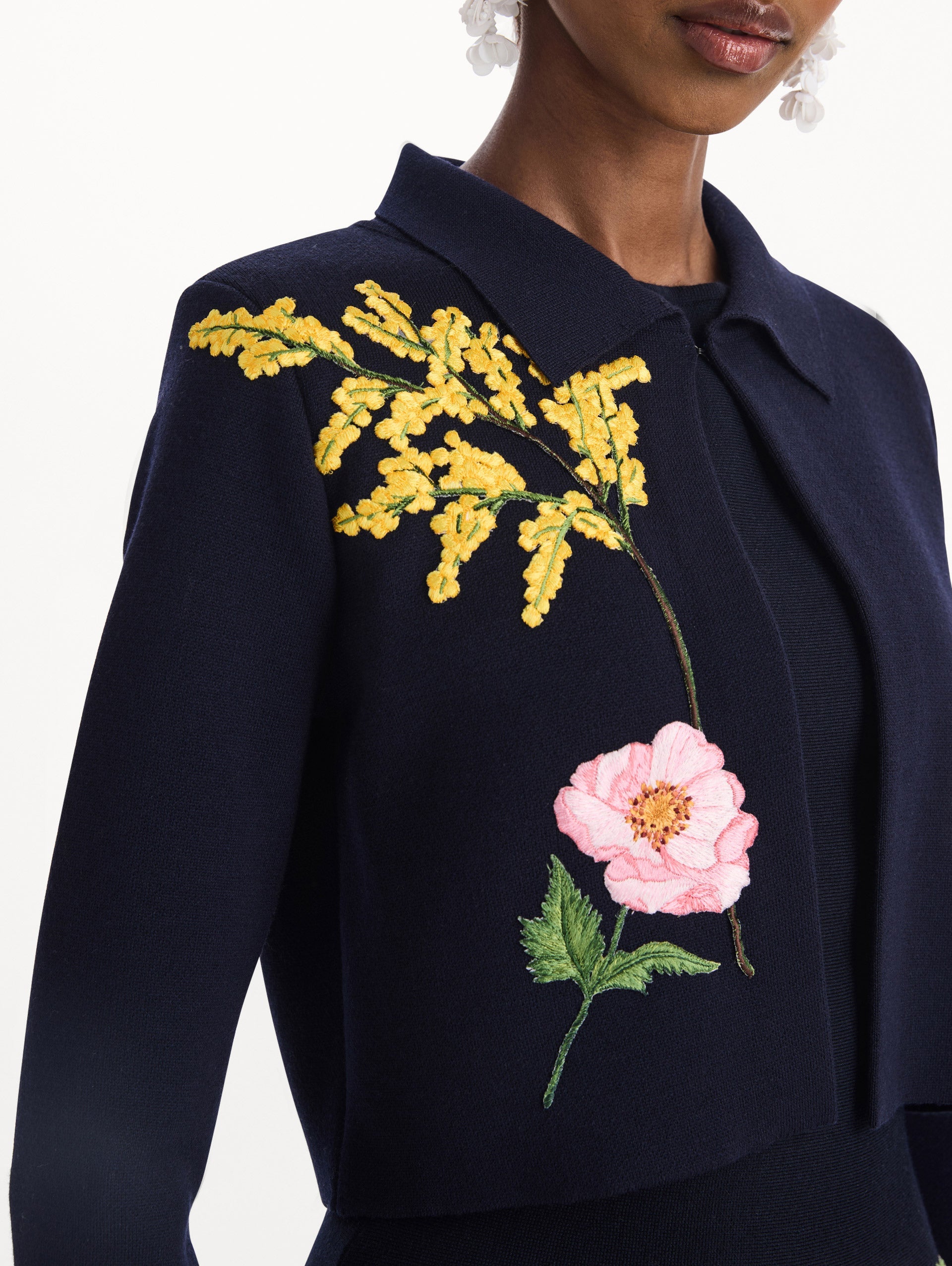 The model is wearing the mixed botanical cropped jacket with delicate embroidery in the color navy. Zoom view.