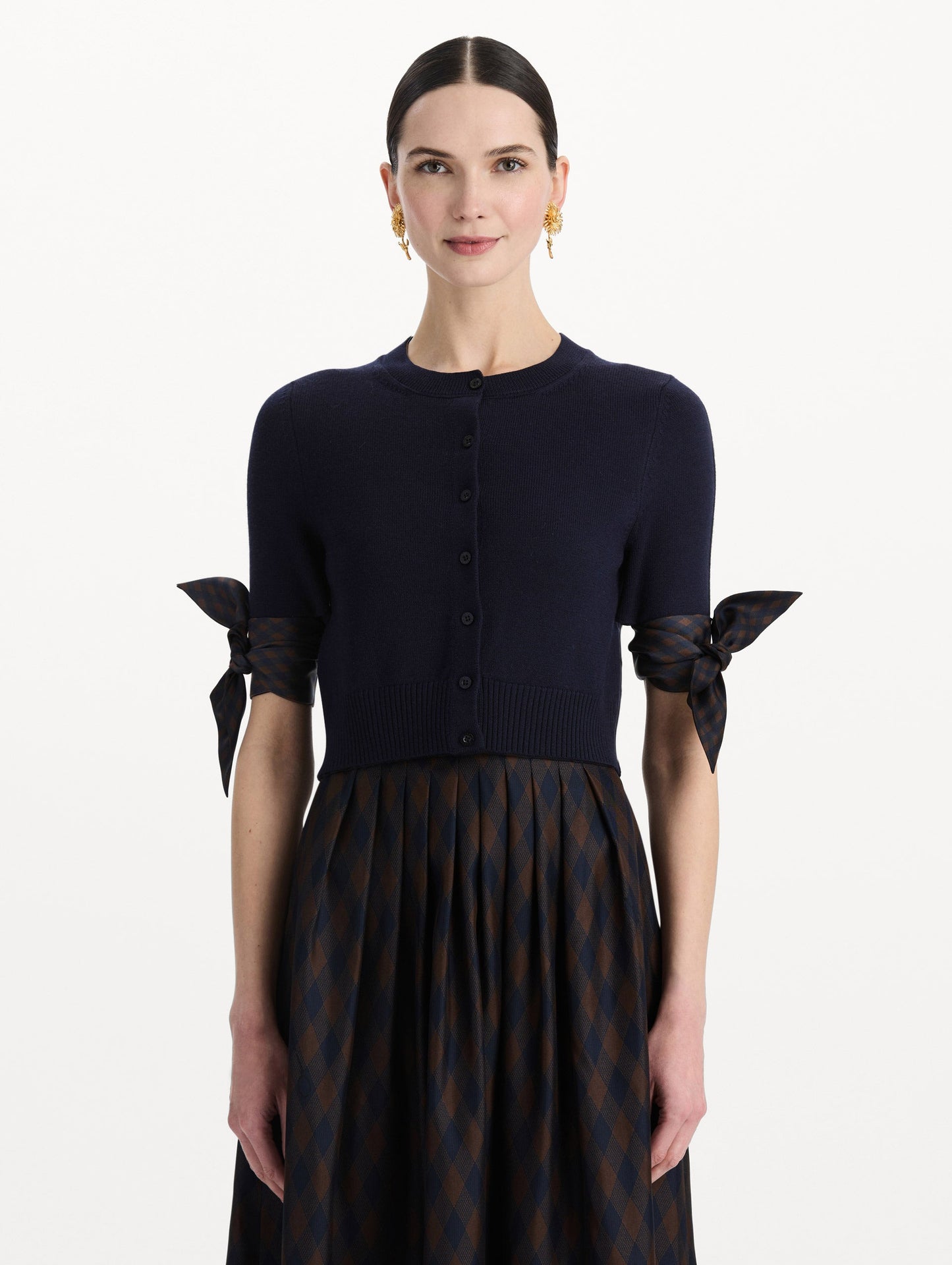 The model is wearing the argyle tie-detailed cardigan in the color navy. Front view.