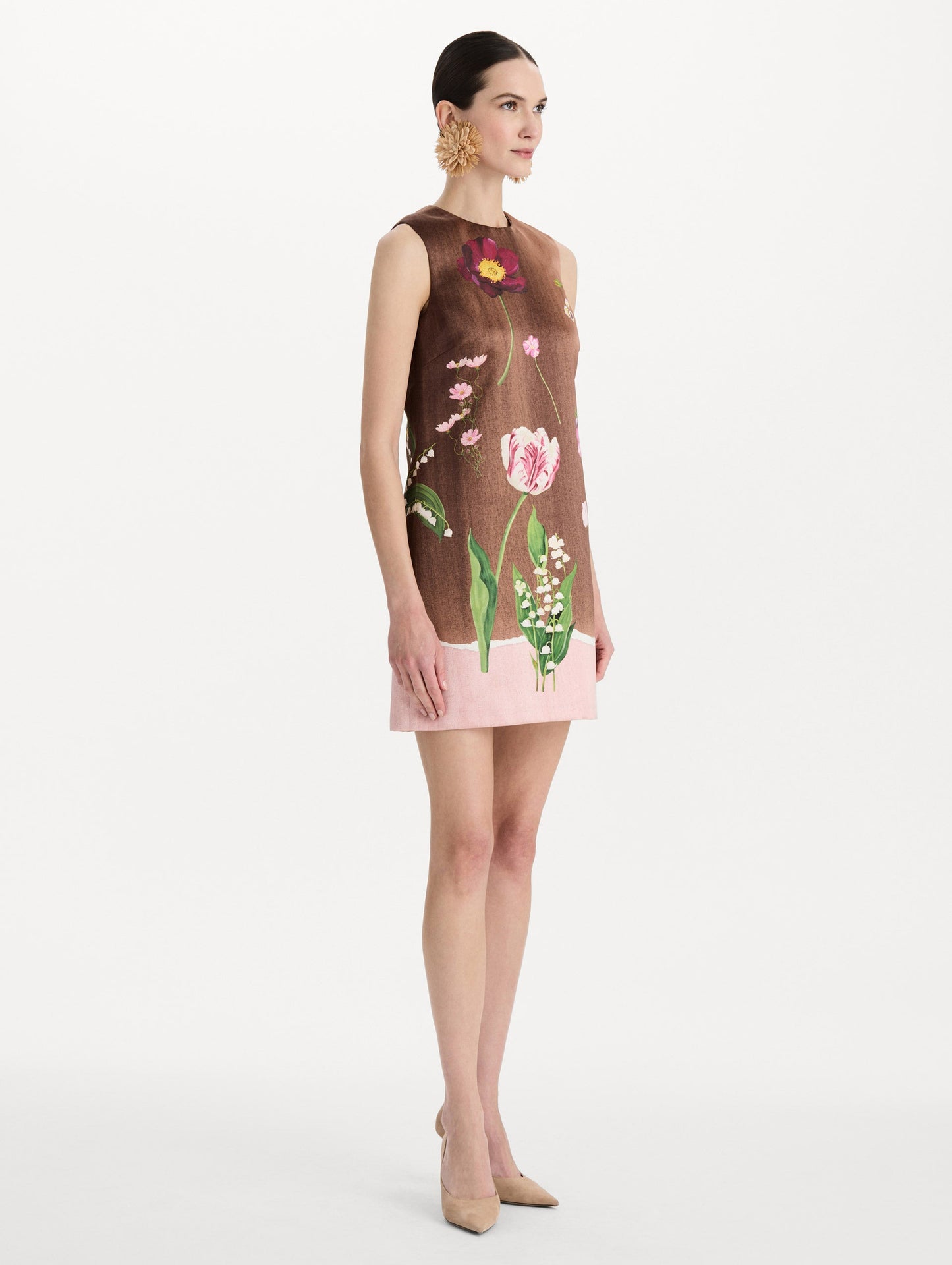 The model is wearing the mixed botanical shift dress with a border print and a sleeveless silhouette. Side view.