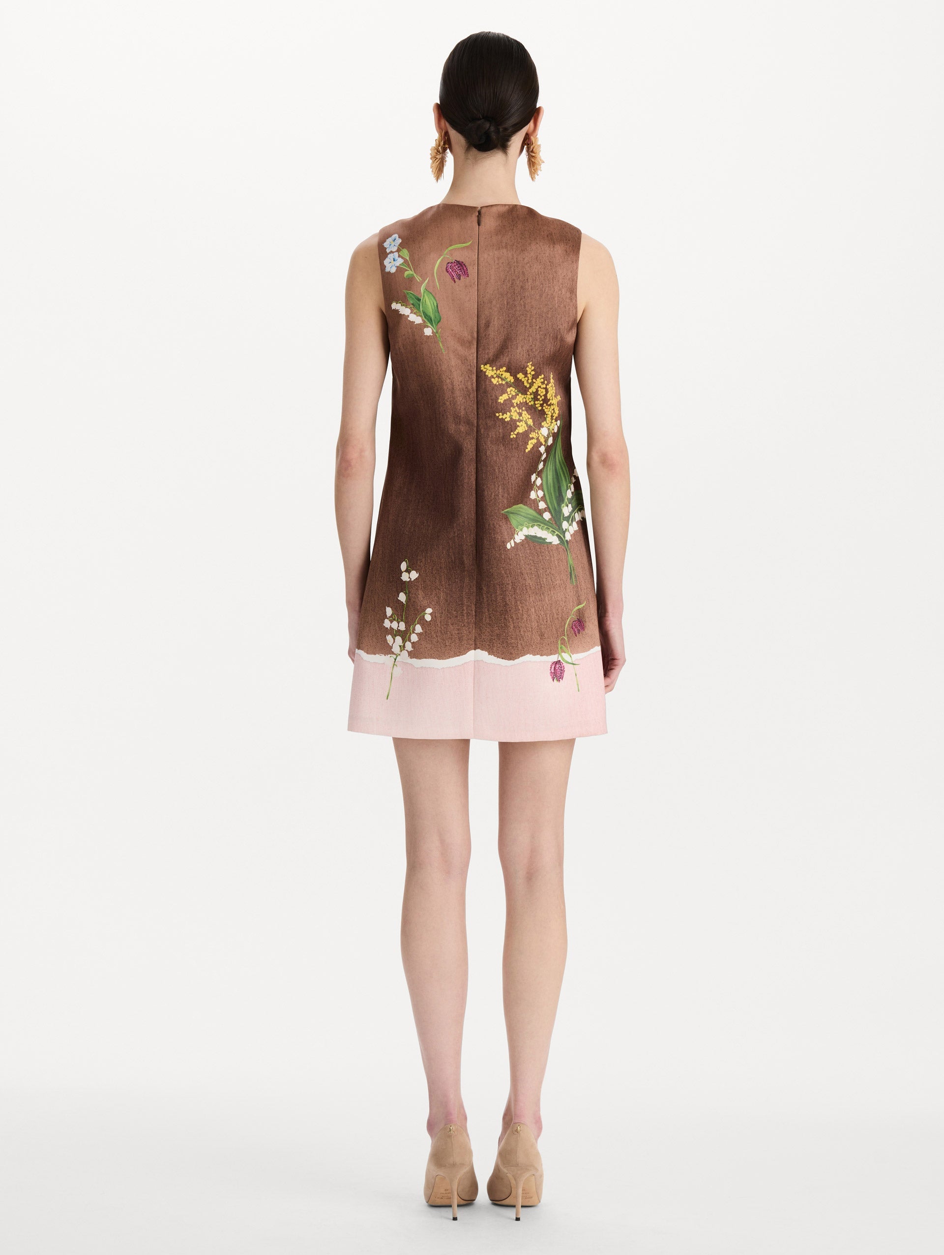 The model is wearing the mixed botanical shift dress with a border print and a sleeveless silhouette. Back view.