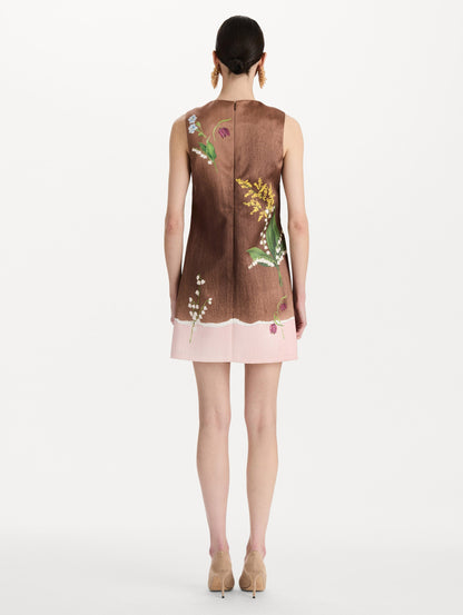 The model is wearing the mixed botanical shift dress with a border print and a sleeveless silhouette. Back view.